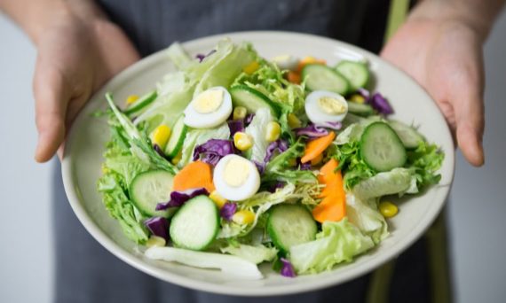 Freshly prepared salad with cucumber, lettuce, carrots, and egg slices presented on a plate.